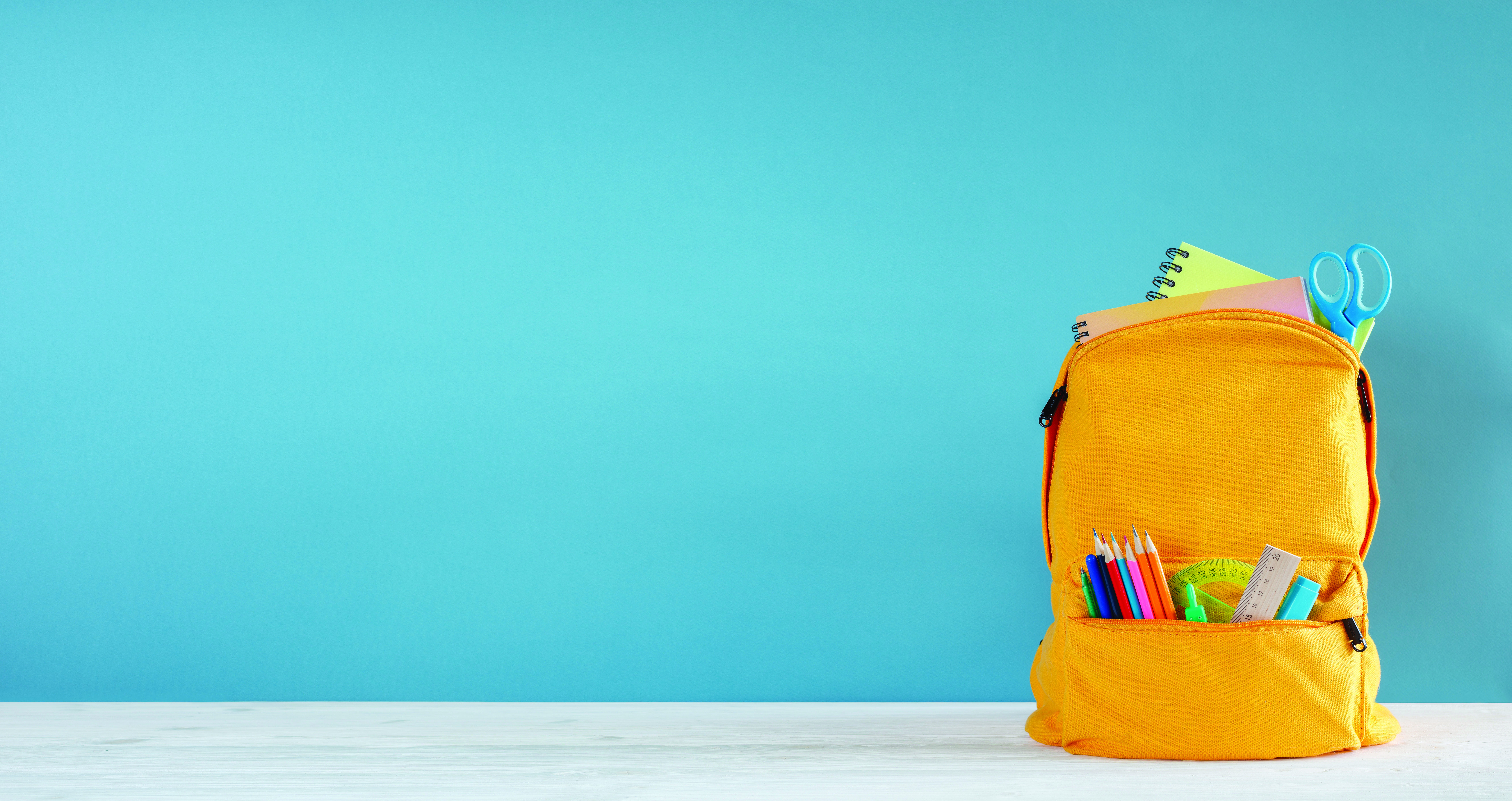 A,Yellow,School,Backpack,With,A,Blue,Wall,Behind,It.