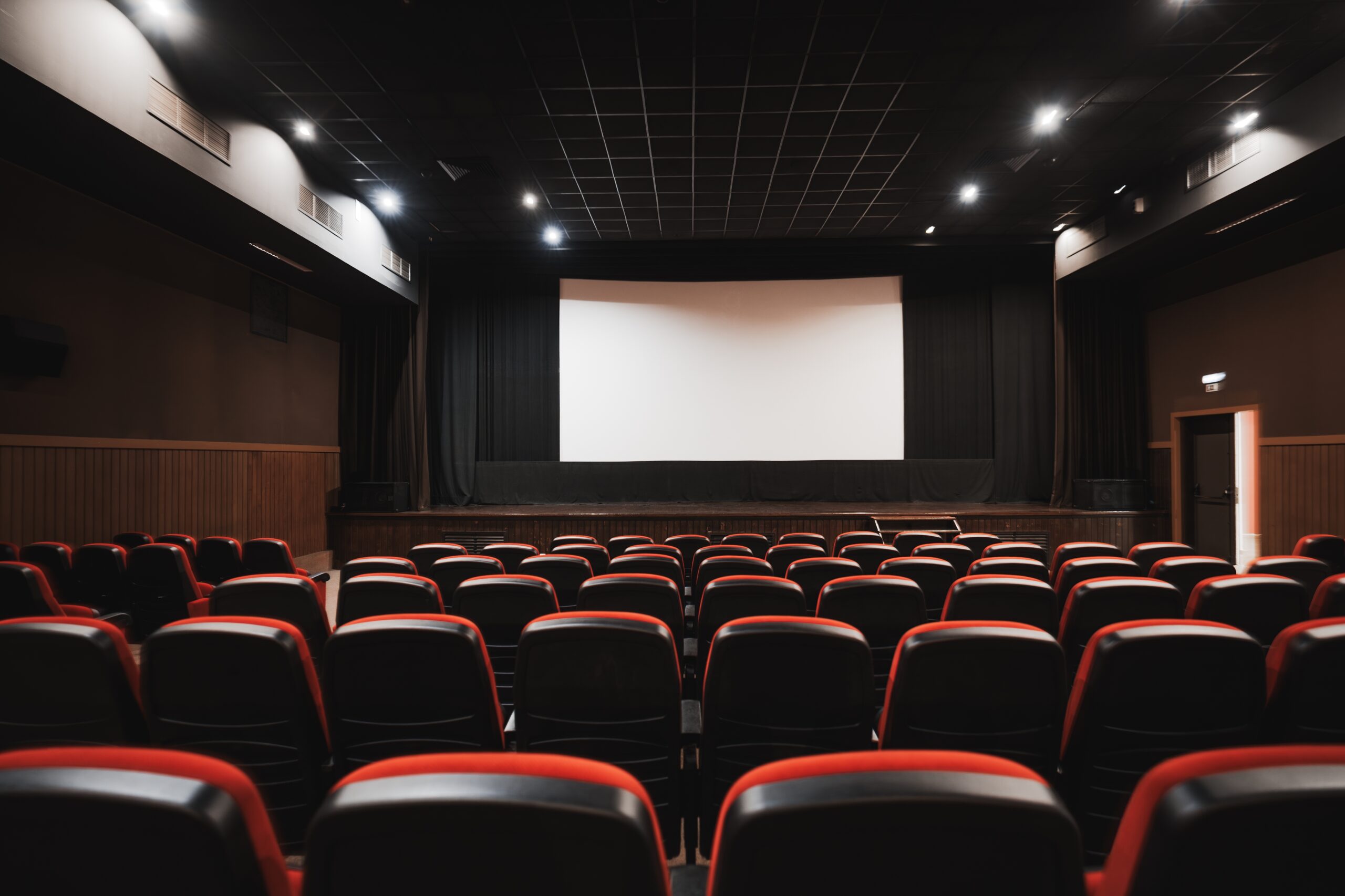 Salle de spectacle aux fauteuils rouges face a une scene illustrant un auditorium