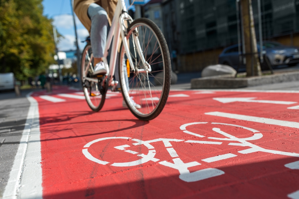 Traffic,,City,Transport,And,People,Concept,-,Woman,Cycling,Along cycliste roulant sur une avenue urbaine equipee dune piste cyclable