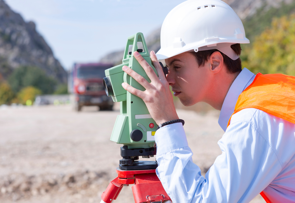 Surveyor,Engineer,Is,Measuring,Level,On,Construction,Site.,Surveyors,Ensure Géomètre étudiant un terrain constructible dans une agglomération