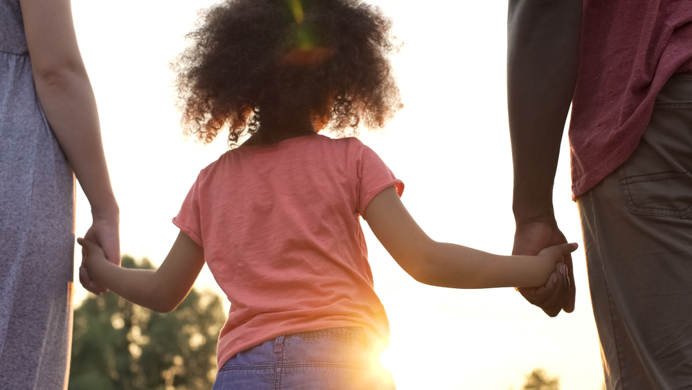 Enfant tenant ses parents par la main, symbole du soutien à la parentalité