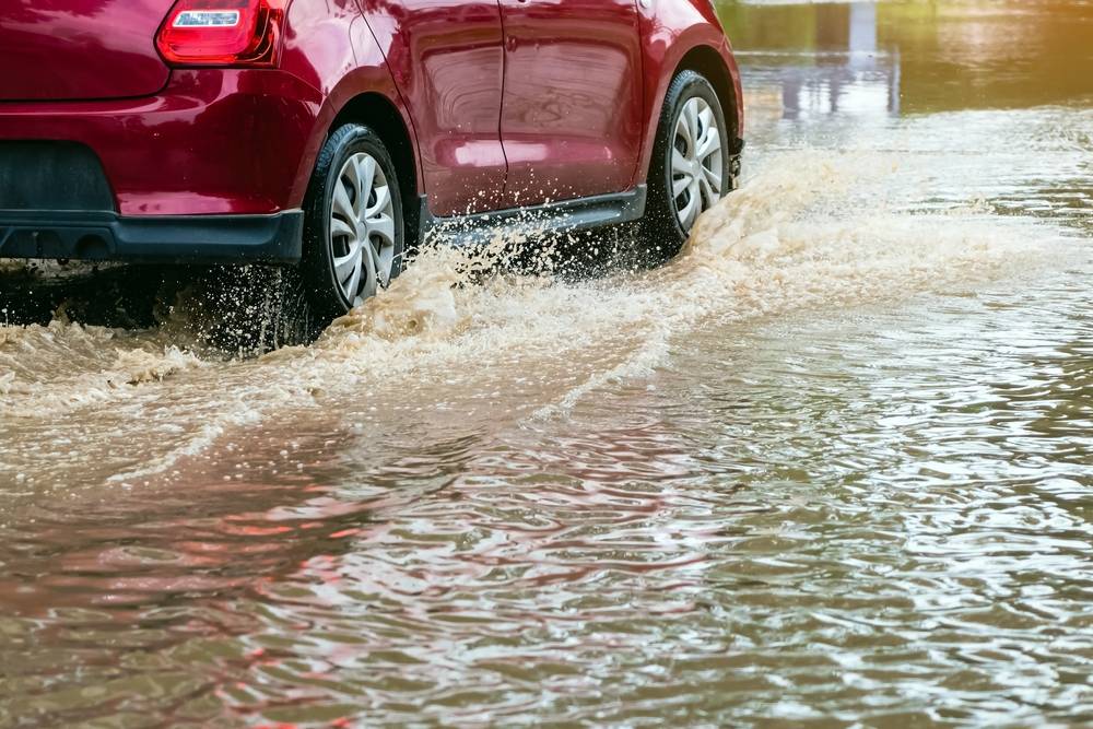 Voiture traversant une route inondée pendant une vigilance orange